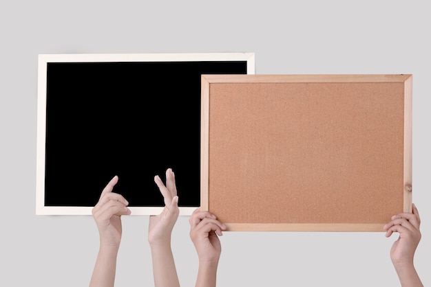 Human hand holding a brown cork board in a frame and blackboard isolated over white wall