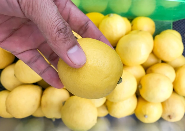 Foto mano umana che tiene un limone su uno sfondo sfocato