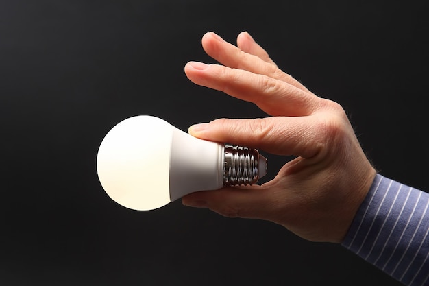 Human hand holding luminous led lamp on dark 
