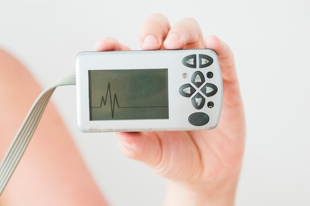 Human hand holding monitor with cardiogram