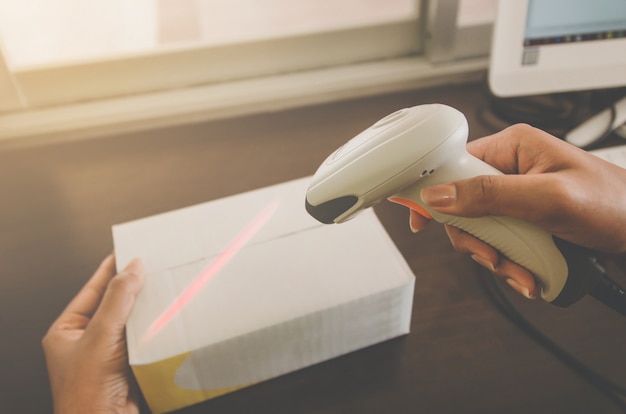 A human hand holding parcel with barcode reader for delivery.