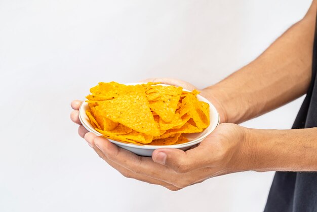 A human hand holding a plate with tortilla chips with a white background