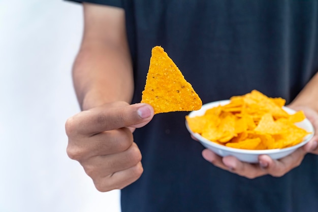 A human hand holding a plate with tortilla chips with a white background