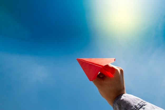 Human hand holding red paper airplane