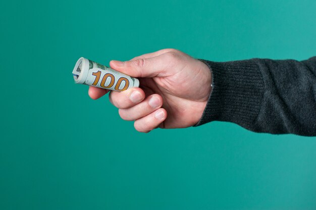 Human hand holding rolled up paper dollar currency