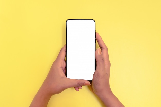 白い画面の背景を持つスマートフォンを持っている人間の手。