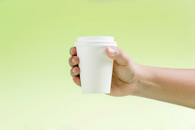 Human hand holding a white plastic cup with colored background