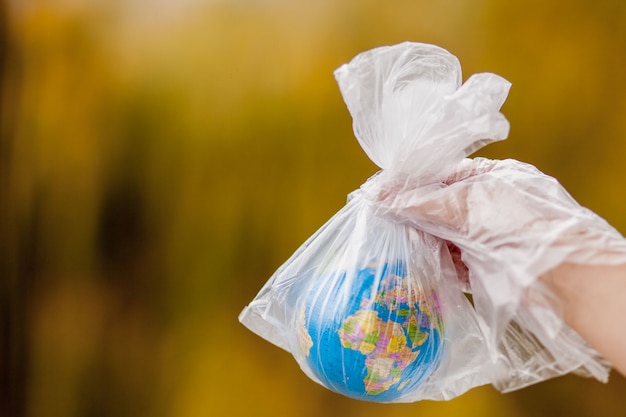 The human hand holds the planet earth in a plastic bag. The concept of pollution by plastic debris. Global warming due to greenhouse effect.