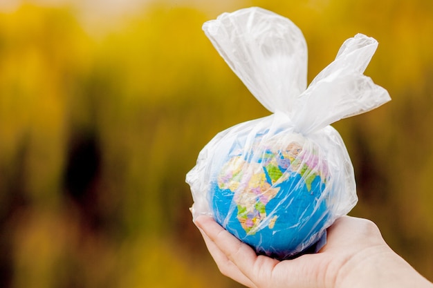 The human hand holds the planet earth in a plastic bag. The concept of pollution by plastic debris. Global warming due to greenhouse effect.