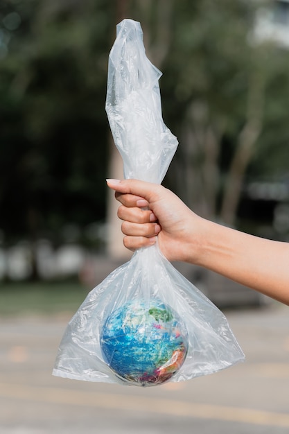 La mano umana tiene il pianeta terra in un sacchetto di plastica. il concetto di inquinamento da detriti di plastica. riscaldamento globale dovuto all'effetto serra