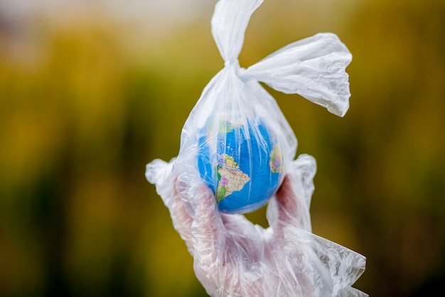 human hand holds the planet earth in a plastic bag