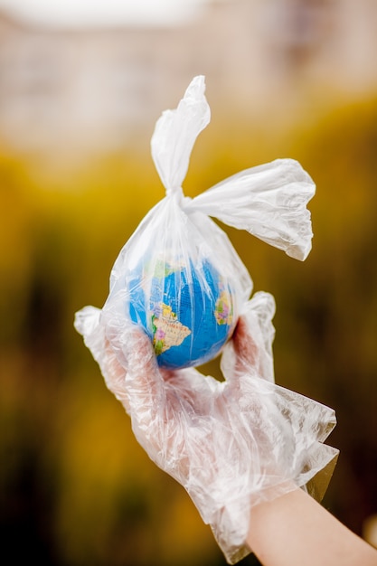 Foto la mano umana tiene il pianeta terra in un sacchetto di plastica