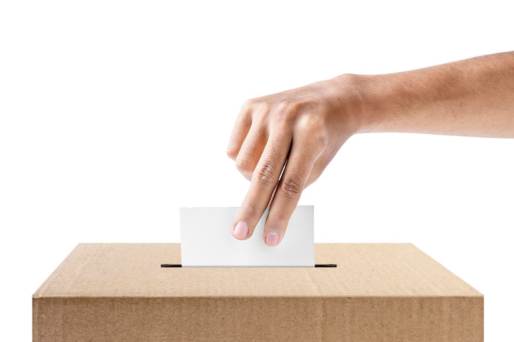 Photo human hand inserts vote paper into ballot box isolated over white background election concept