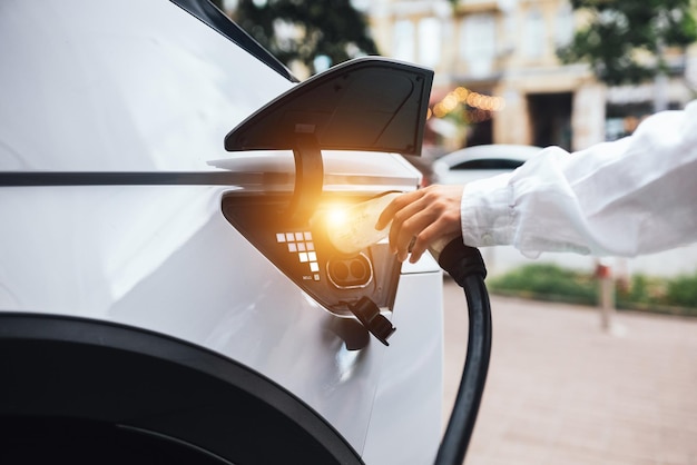 人間の手が電気自動車の充電ノズルを持っています