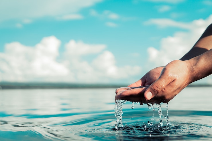 Photo human hand is touching water on the river,water crisis