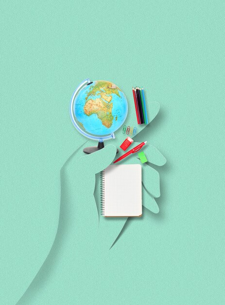 Photo human hand made of paper holding accessories and belongings for studying, traveling, writing on green background. contemporary colorful and conceptual bright art collage, mockup with copyspace.