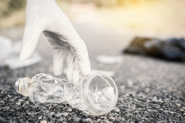 Human hand picking up empty of bottle plastic on park 