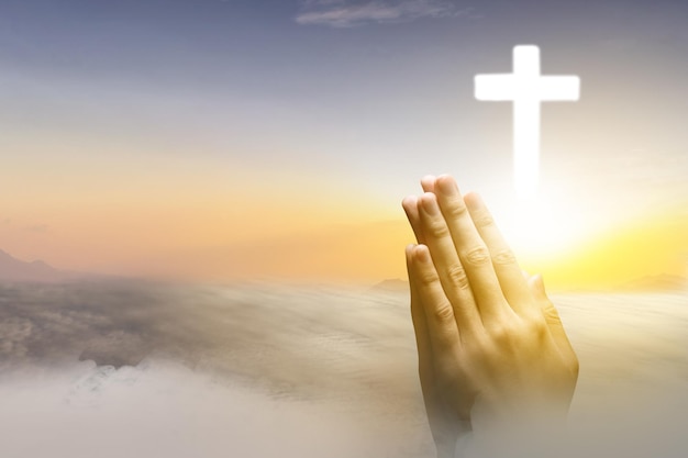 Human hand praying with Christian cross