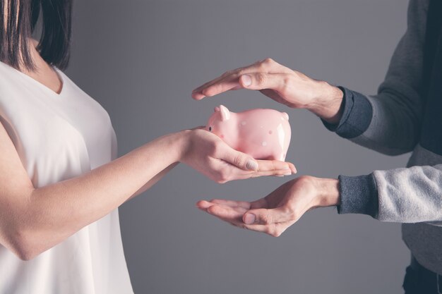 Human hand protecting a piggy bank