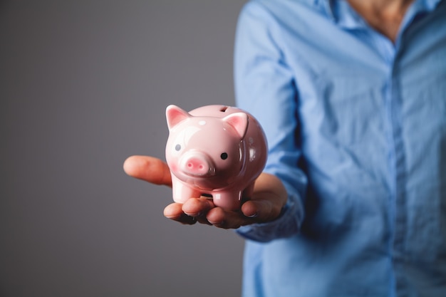 Human hand protecting a piggy bank