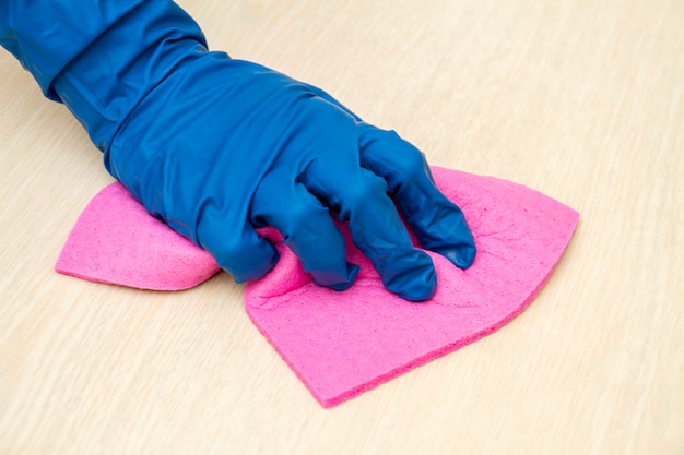 A human hand in a protective glove disinfects the table with a cleaning cloth for viruses prevention