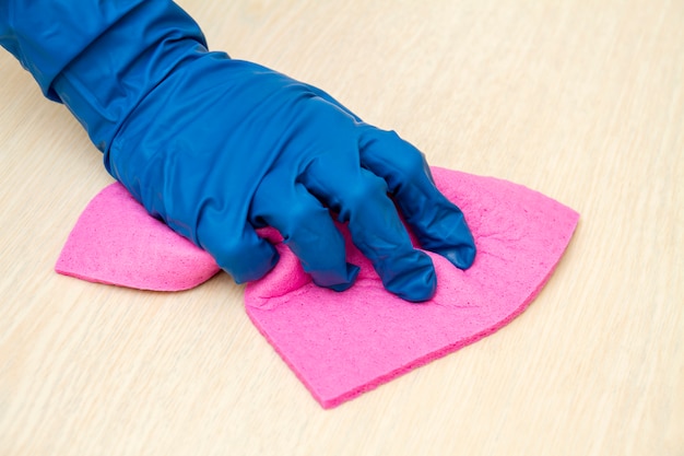 a human hand in a protective glove disinfects the table with a cleaning cloth for viruses prevention