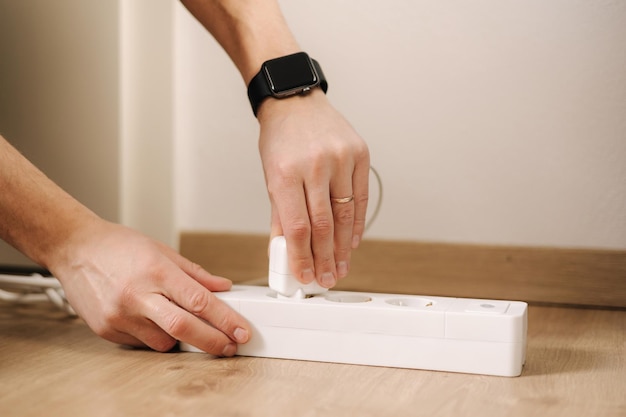 Photo human hand puts the charger into the extension cord white cable connector