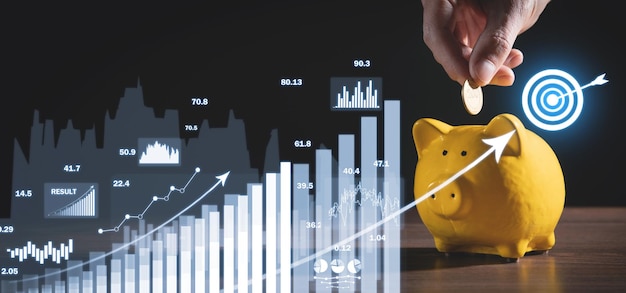 Human hand putting coin to piggy bank Achieve business goals with growth graphs