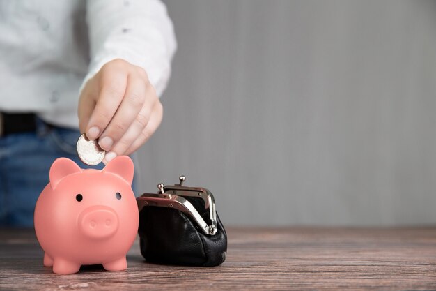 Human Hand Putting Coin In pink Piggy Bank