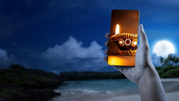 Human hand showing Diya oil lamps for the Diwali festival on the mobile phone screen Diwali Festival The Hindu Festival of Lights celebration