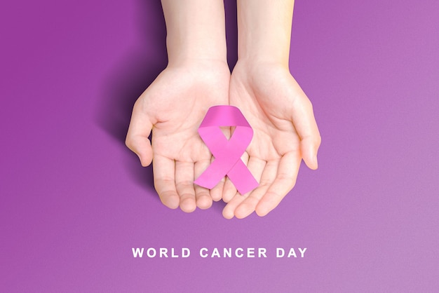 human hand showing a purple ribbons on a colored background. world cancer day concept