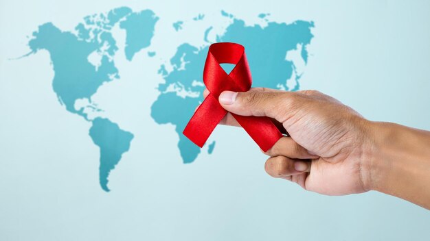 Human hand showing red ribbon awareness World Aids Day concept