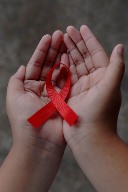 Human hand showing red ribbon. World Cancer Day concept