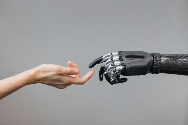 The human hand and the siber hand bionic prosthesis make a handshake and greeting modern