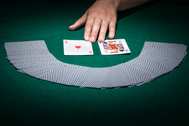 Human hand touching playing card on poker table