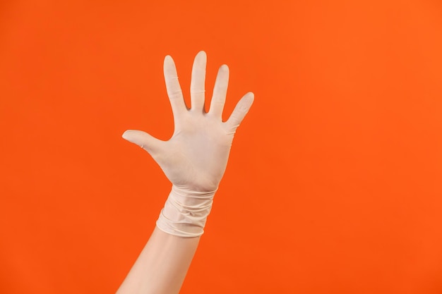 Human hand in white surgical gloves showing number five with hand or waving hand to greeting.