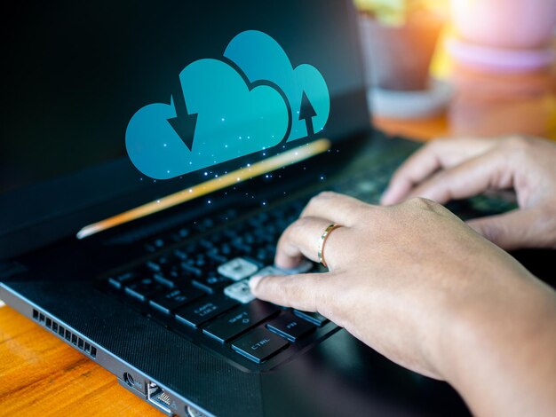 Человеческая рука, работающая над компьютером и значком облака Концепция облачных вычислений соединяет информацию и технологии коммуникационного оборудования с облачными вычислениями