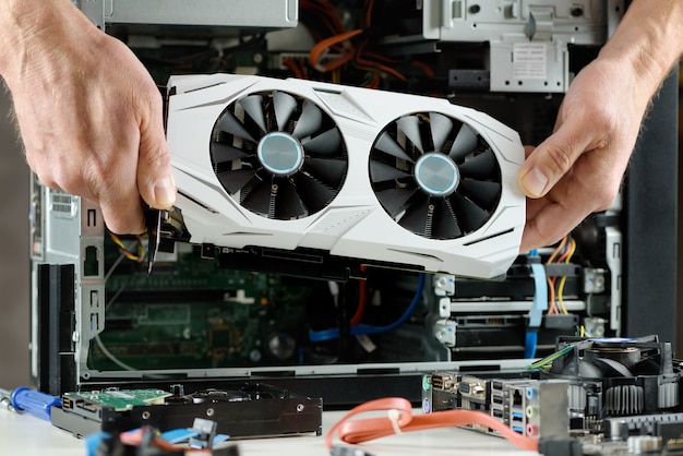 Human hands are inserting a video card into a computer.