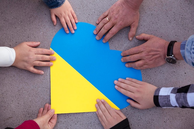 Mani umane intorno a un cuore con i colori della bandiera ucraina solidarietà unita e sostegno all'ucraina no alla guerra