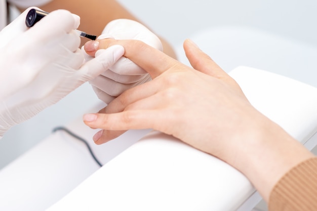 Human hands covering clear varnish on female nails