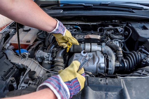 Human hands examining car engine in protective gloves close up