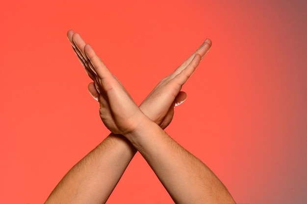 Human hands folded crosswise which symbolize the wings of a bird or the sign of xx isolated on a red background