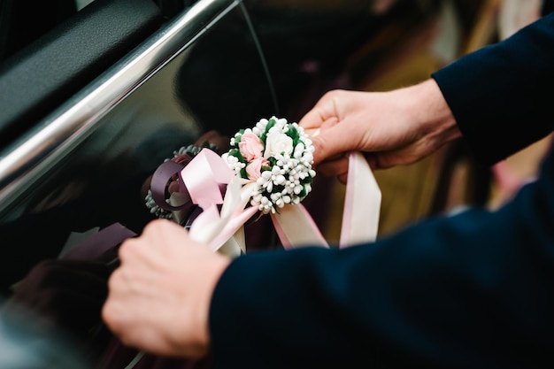 Human hands hold a decor a car decorated with flowers Wedding car with beautiful decorations Flower decor