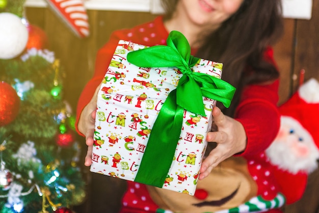 Human hands holding a gift. Girl holds out a Christmas gift in a box