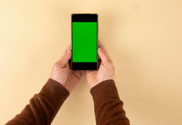 Human hands holding smartphone with green screen background