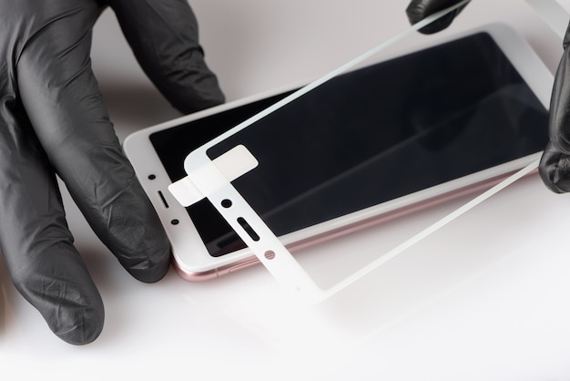 Human hands removing a protective film from the screen of a smartphone