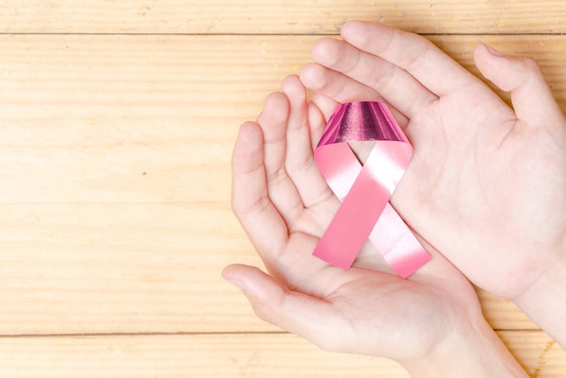 Human hands showing pink awareness ribbon