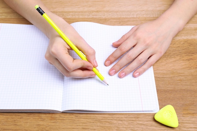 Human hands with pencil writing on paper and erase rubber on wooden table background