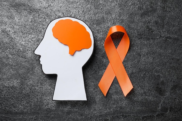 Photo human head cutout brain and orange ribbon on grey table flat lay multiple sclerosis concept