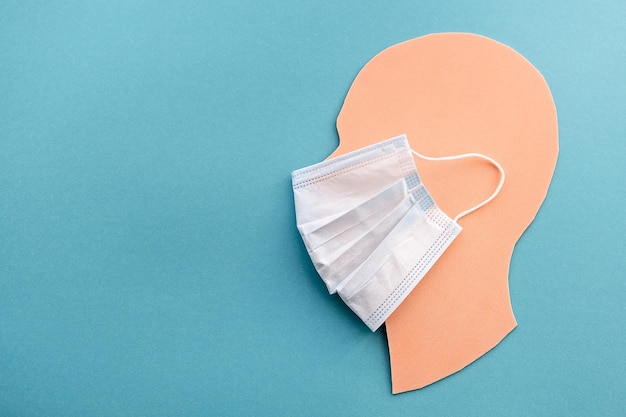 Human head made of paper in a medical mask on a blue background